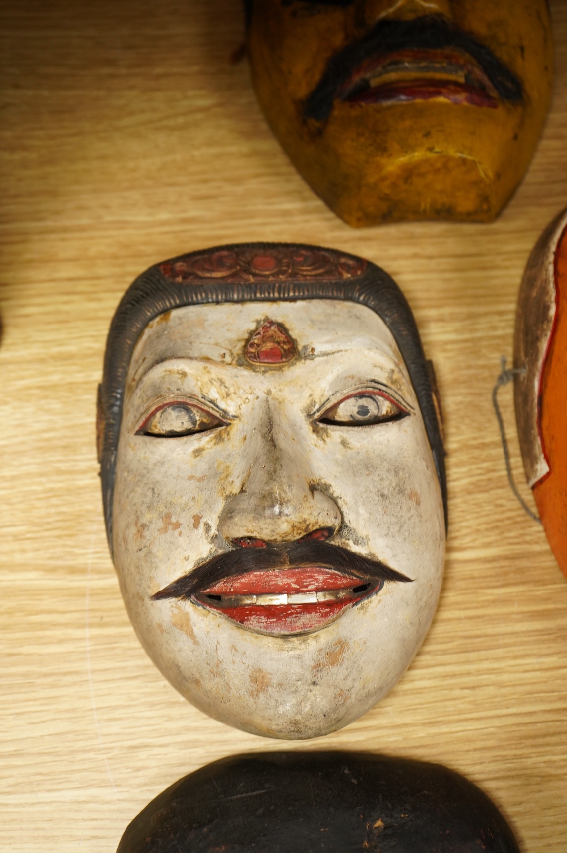 A collection of seven Nepalese, African and Indonesian masks to include a Magar example and one from the Dan Tribe, Liberia, largest 40cm